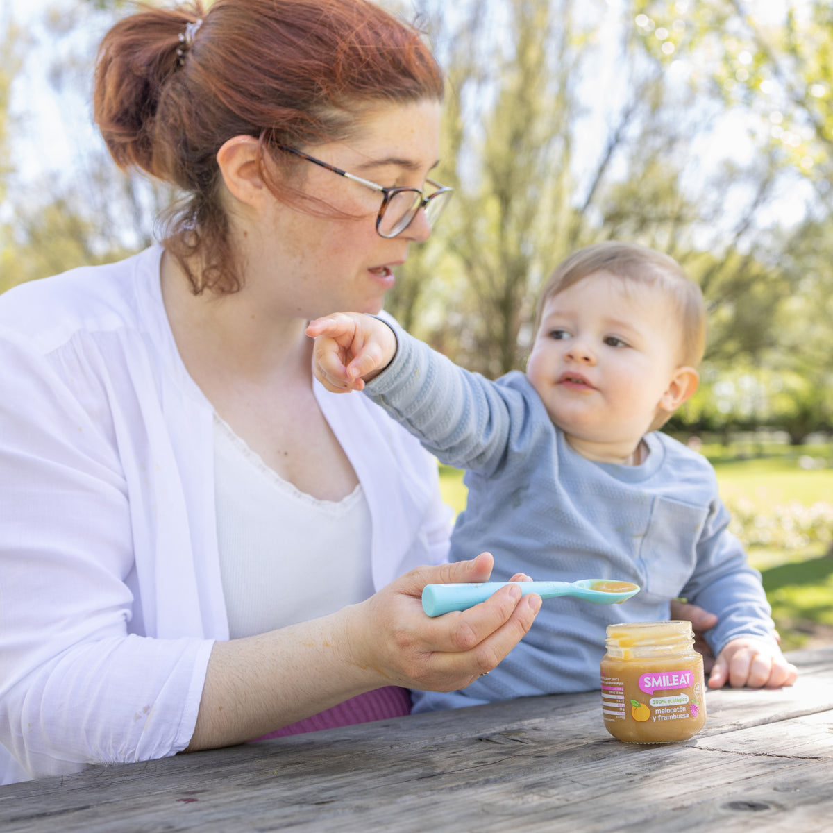 Mãe no parque com bebé ao colo e tarrito biológico – ingredientes reais para refeições fora de casa