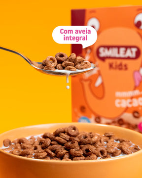Cereais de cacau SMILEAT Kids com aveia integral, servidos numa taça com leite.