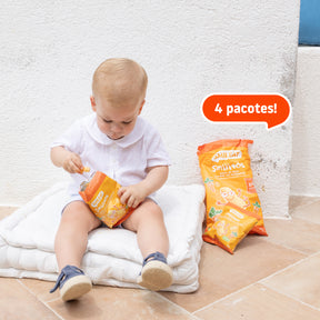 Criança com pacote de snack de milho, cenoura e aveia – lanche biológico com ingredientes reais