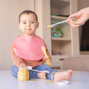 Bebé sentado a comer tarrito de fruta biológica – feito com ingredientes reais