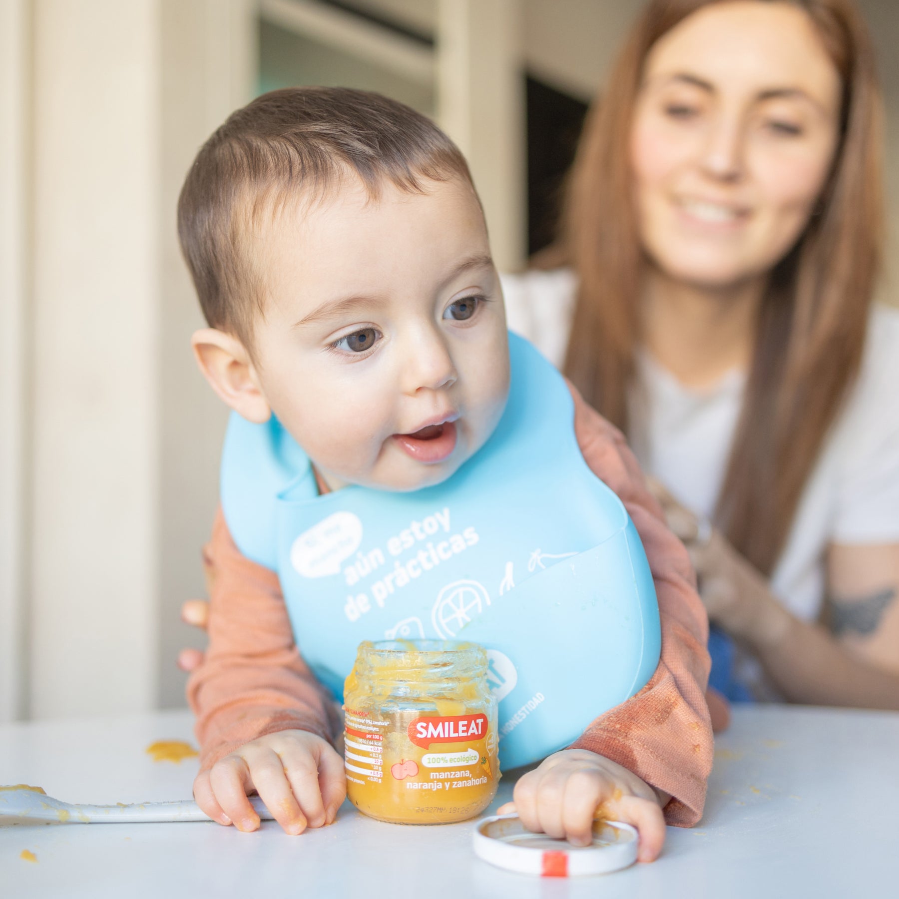 Bebé a gatinhar com tarrito de comida biológica à frente – comida infantil com ingredientes honestos
