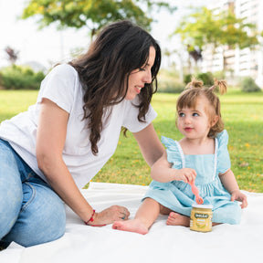 Criança com a mãe a comer tarrito biológico – comida infantil feita com ingredientes reais